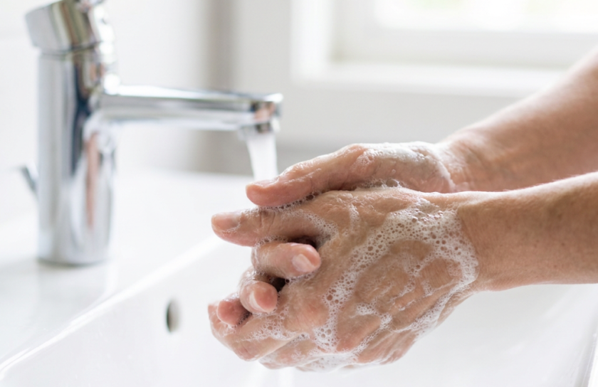 Washing hands with rich foamy soap lather at a bathroom sink, illustrating daily antiseptic cleansing